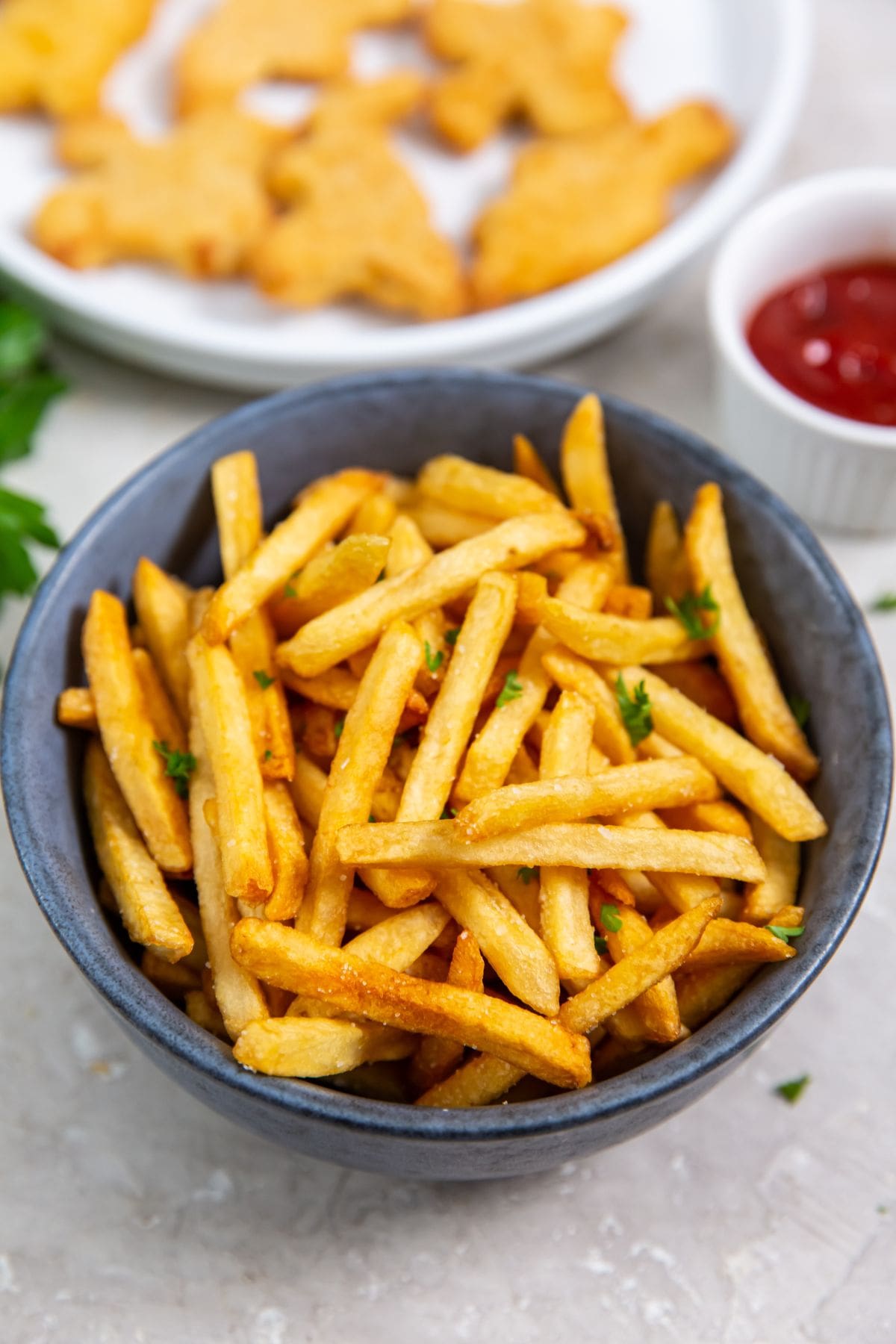 Air Fryer Frozen French Fries fries served with ketchup and dipping sauce.