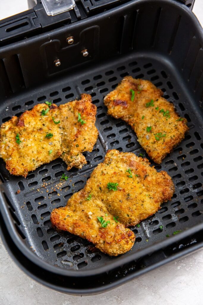 Air Fryer Breaded Chicken Thighs black air fryer with cooked chicken inside.