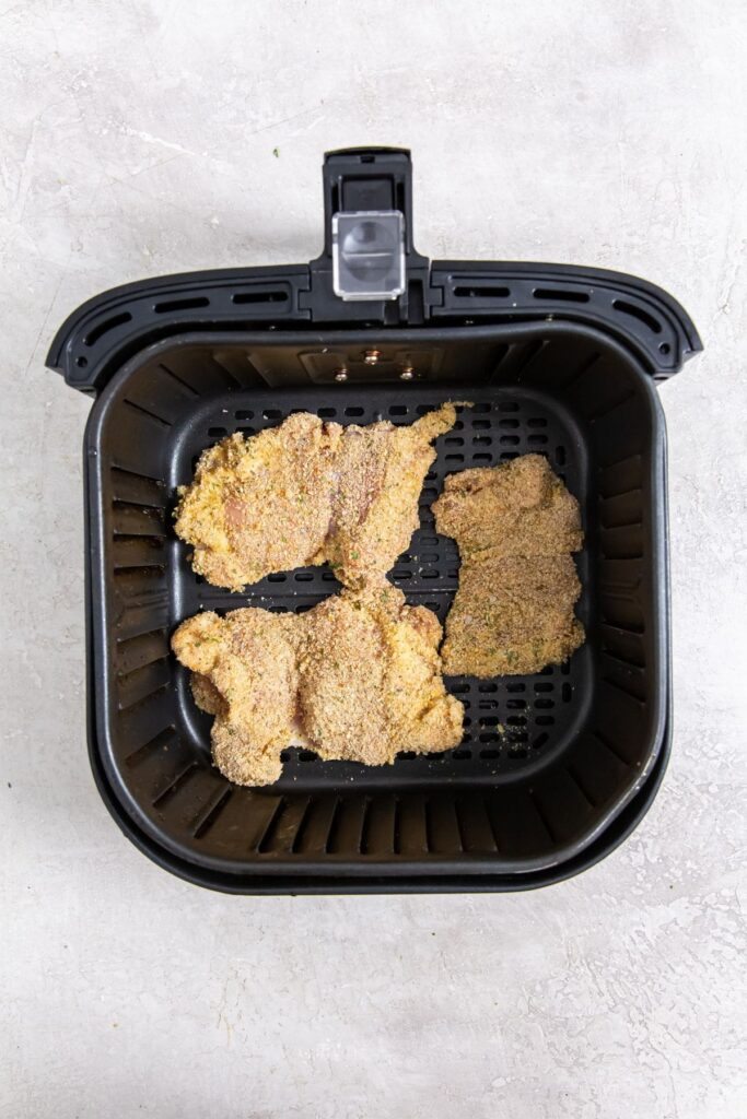 Air Fryer Breaded Chicken Thighs black air fryer with raw chicken inside