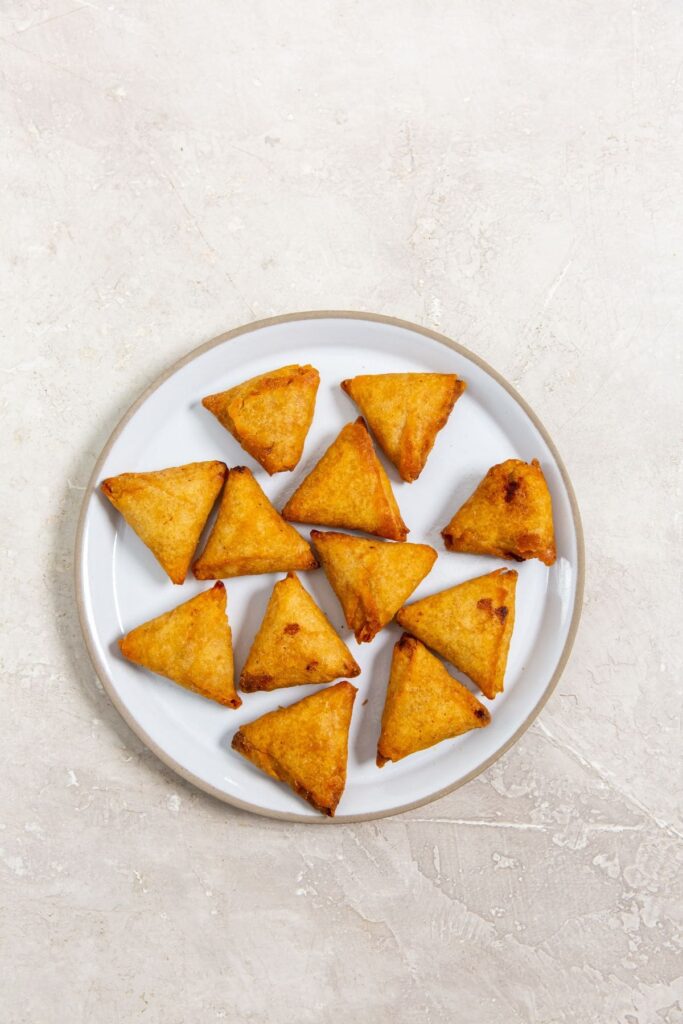 Air Fryer Mini Chicken Tikka Samosas A plate full of mini chicken tikka samosas, on a white surface.