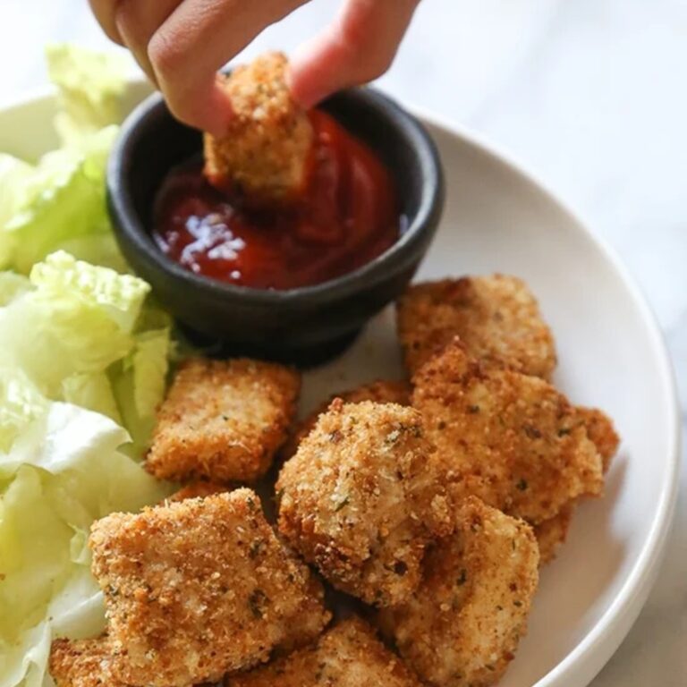 WW Air Fryer Recipes a Person's Hand Dipping a Chicken Nugget into Ketchup on a Plate of Chicken Nuggets