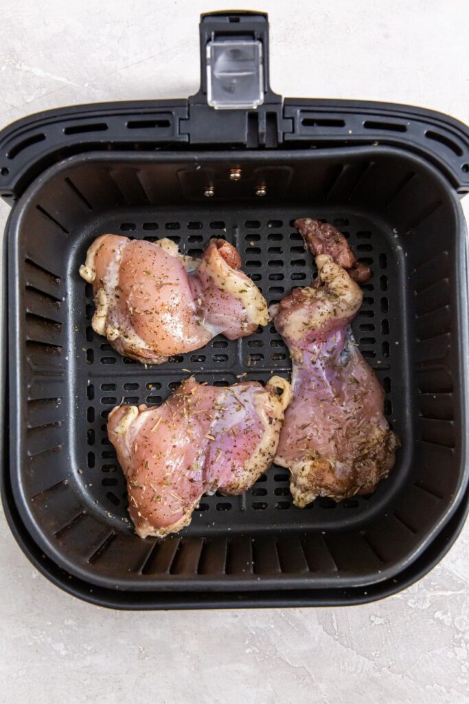 Easy Air Fryer Boneless Skinless Chicken Thighs black air fryer with raw chicken inside