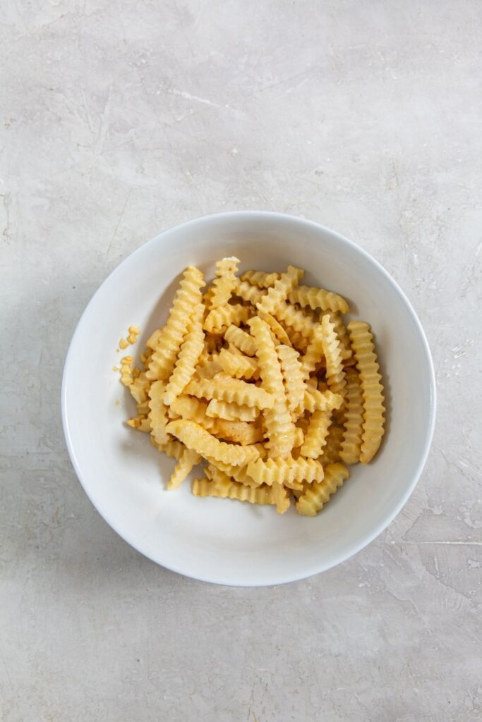 Air Fryer Crinkle Cut French Fries White bowl with frozen fries.