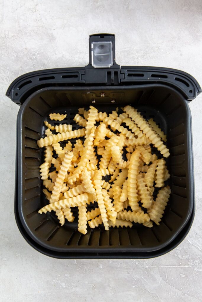 Air Fryer Crinkle Cut French Fries frozen fries inside black air fryer basket.