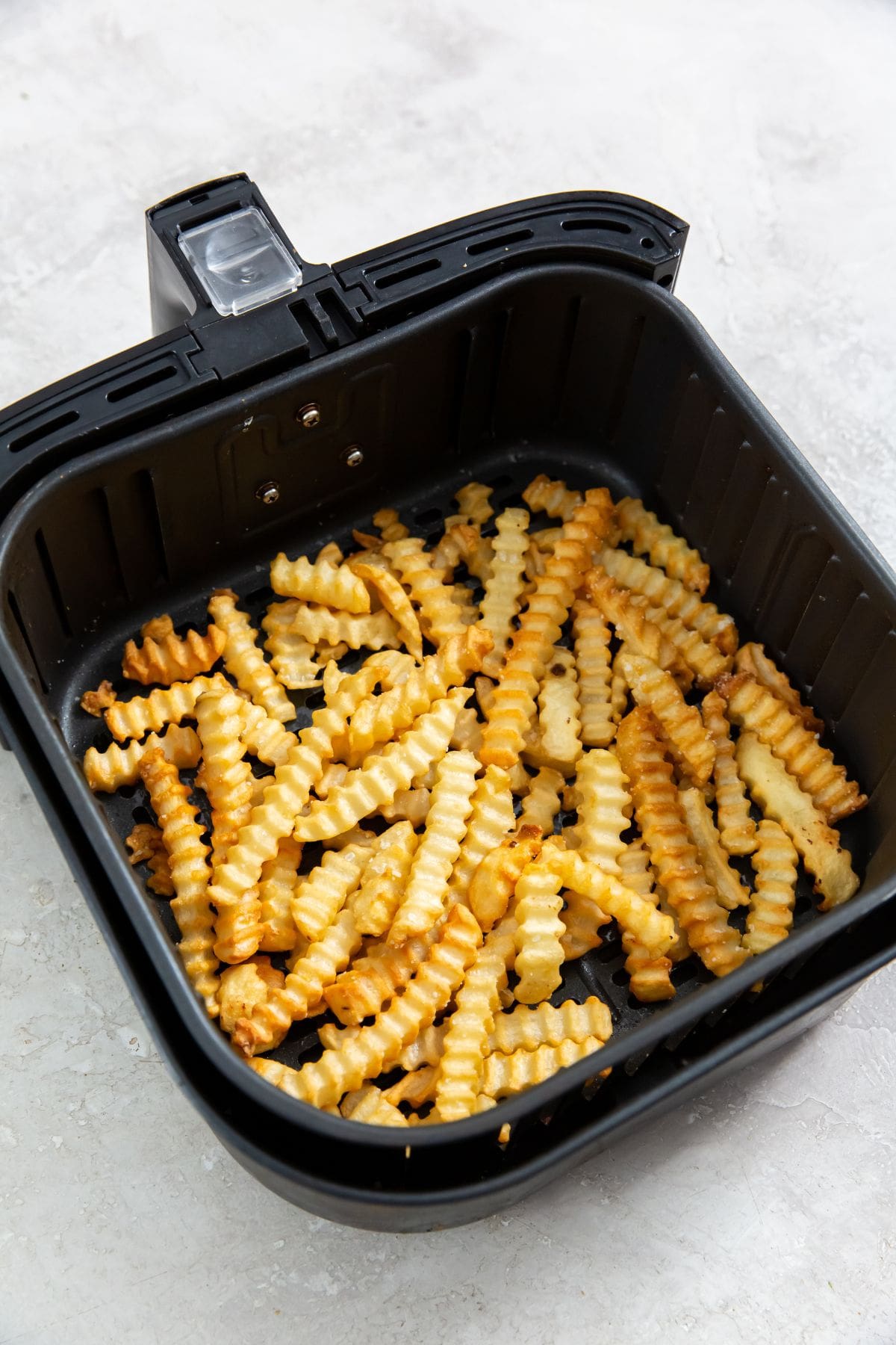 Air Fryer Crinkle Cut French Fries cooked French fries inside a air fryer basket.