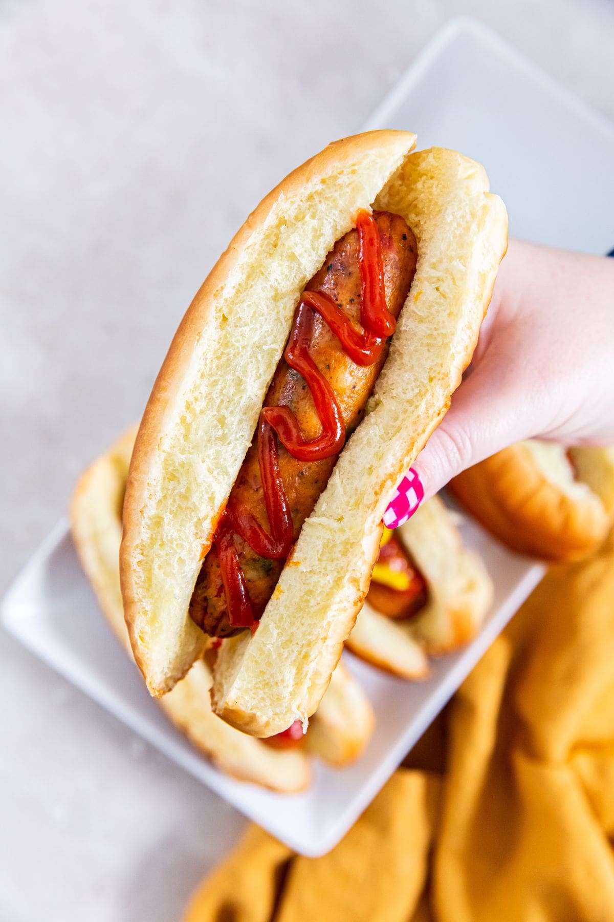 Air Fryer Frozen Chicken Sausage A person holding a sausage on a plate.