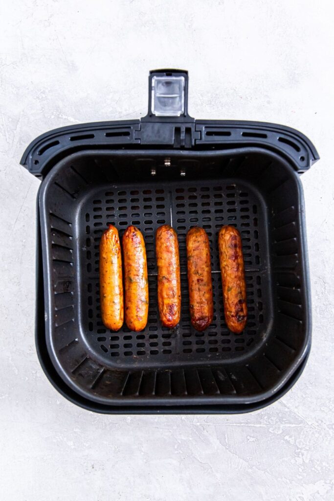 Air Fryer Frozen Chicken Sausage Four sausages in an air fryer.