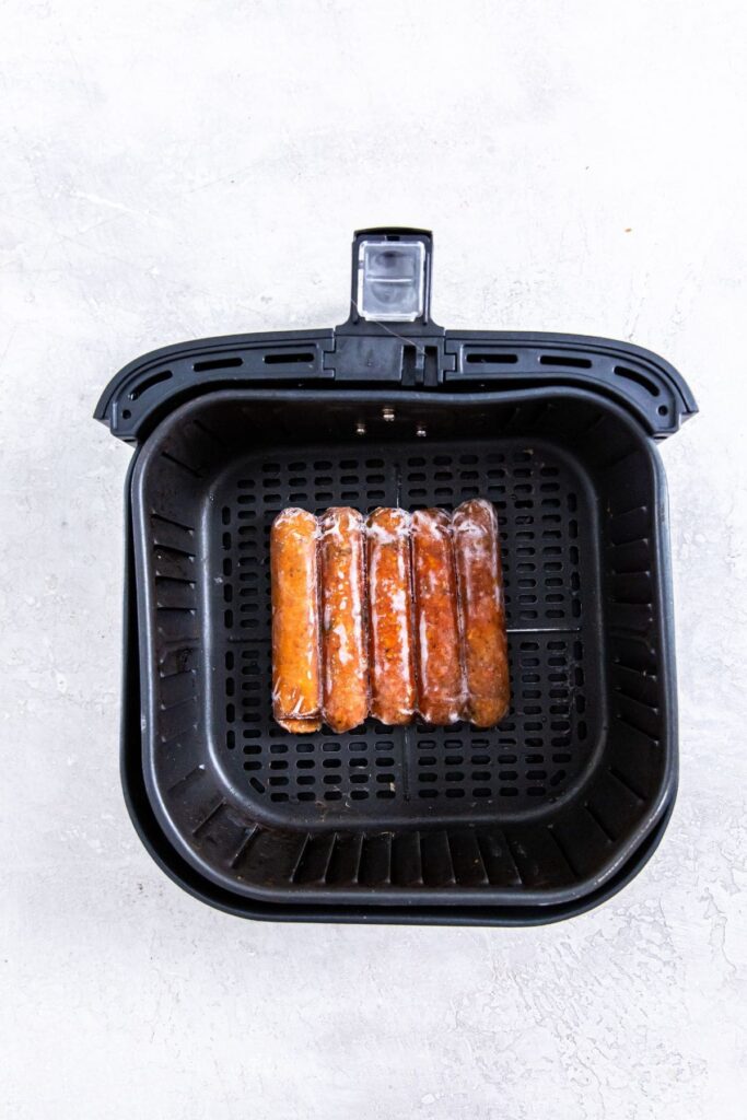 Air Fryer Frozen Chicken Sausage Frozen sausage cooked in an air fryer and placed on a white surface.