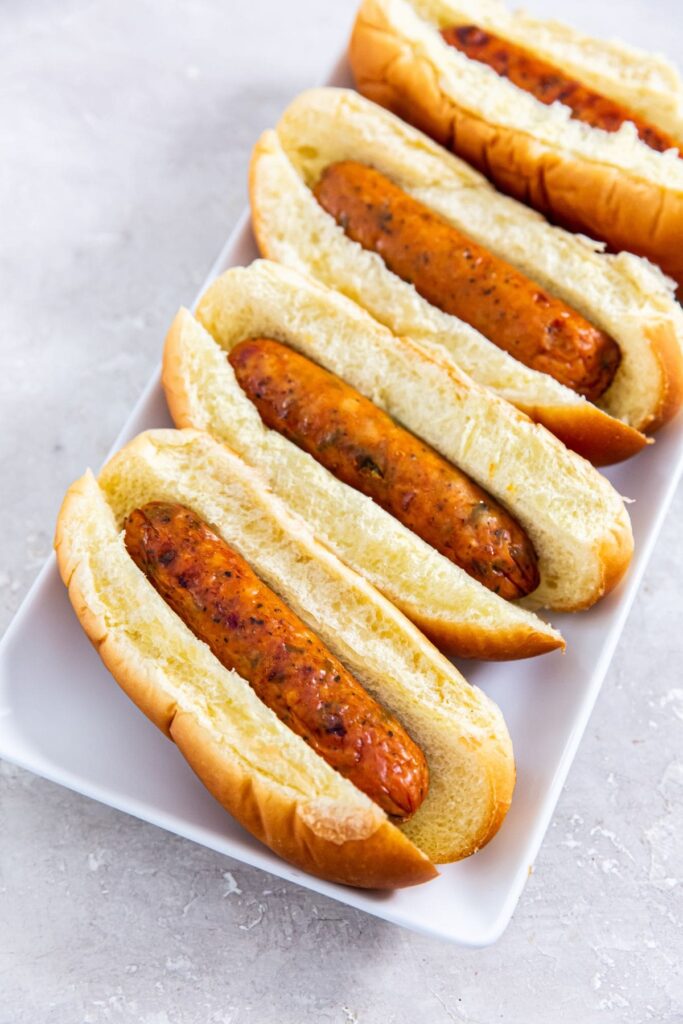 Air Fryer Frozen Chicken Sausage Four air-fried sausages on a white plate.