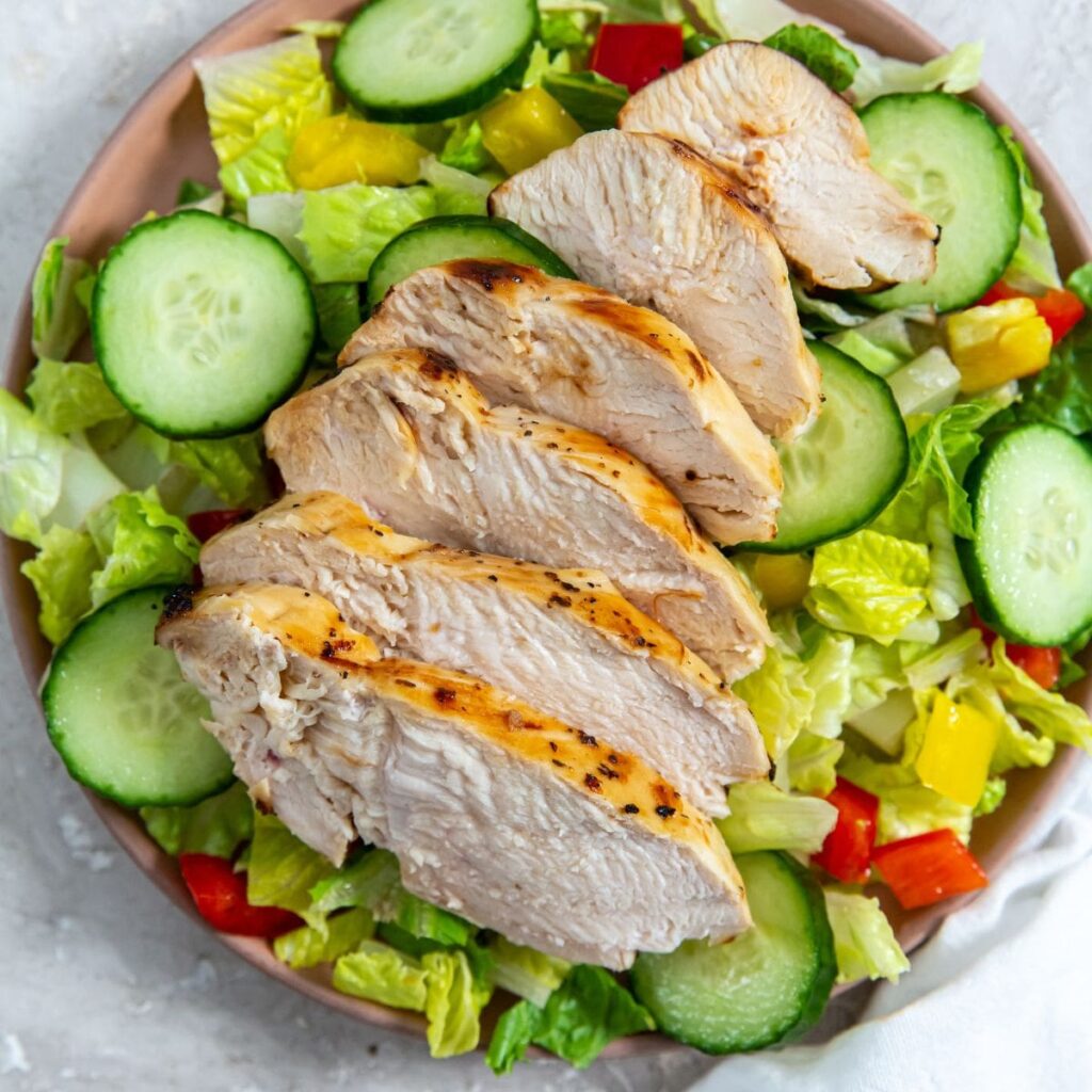 Air Fryer Italian Chicken Breast Sliced on Top of a Salad in a Bowl