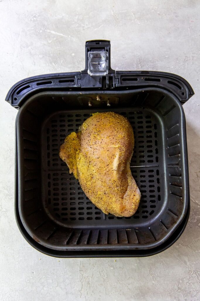 Air Fryer Lemon Pepper Chicken Breasts An air fryer cooking lemon pepper chicken breasts.