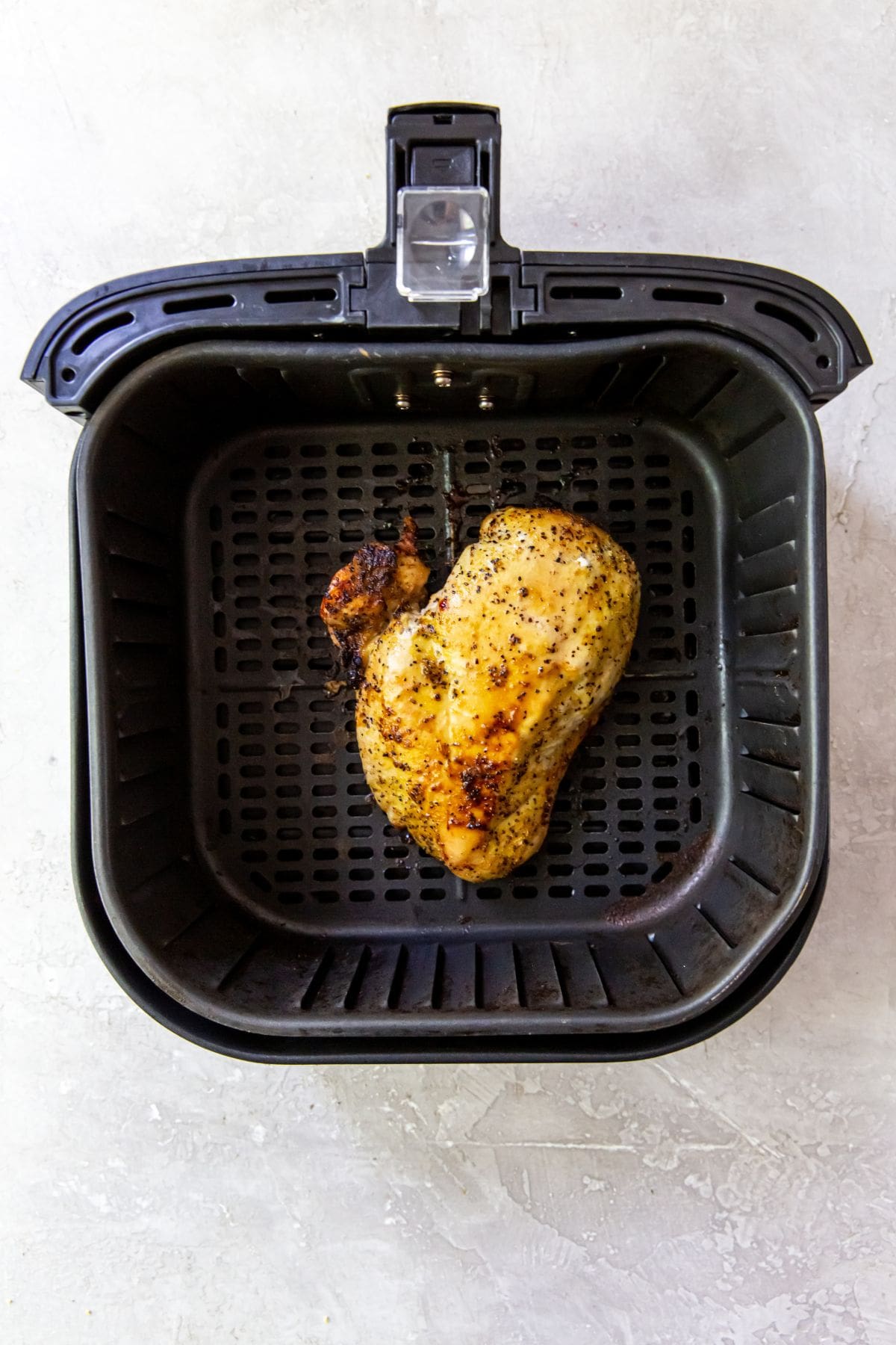 Air Fryer Lemon Pepper Chicken Breasts An air fryer perfectly cooking lemon pepper chicken breasts.