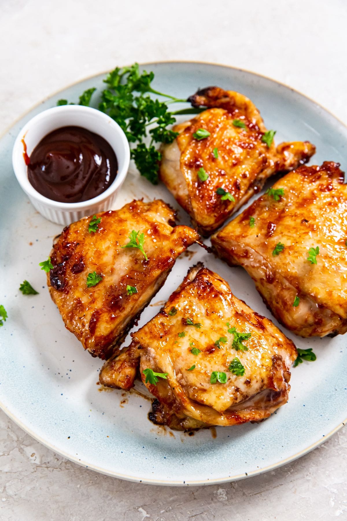 Air Fryer BBQ Chicken Thighs blue plate with chicken thighs and bbq sauce on the plate.