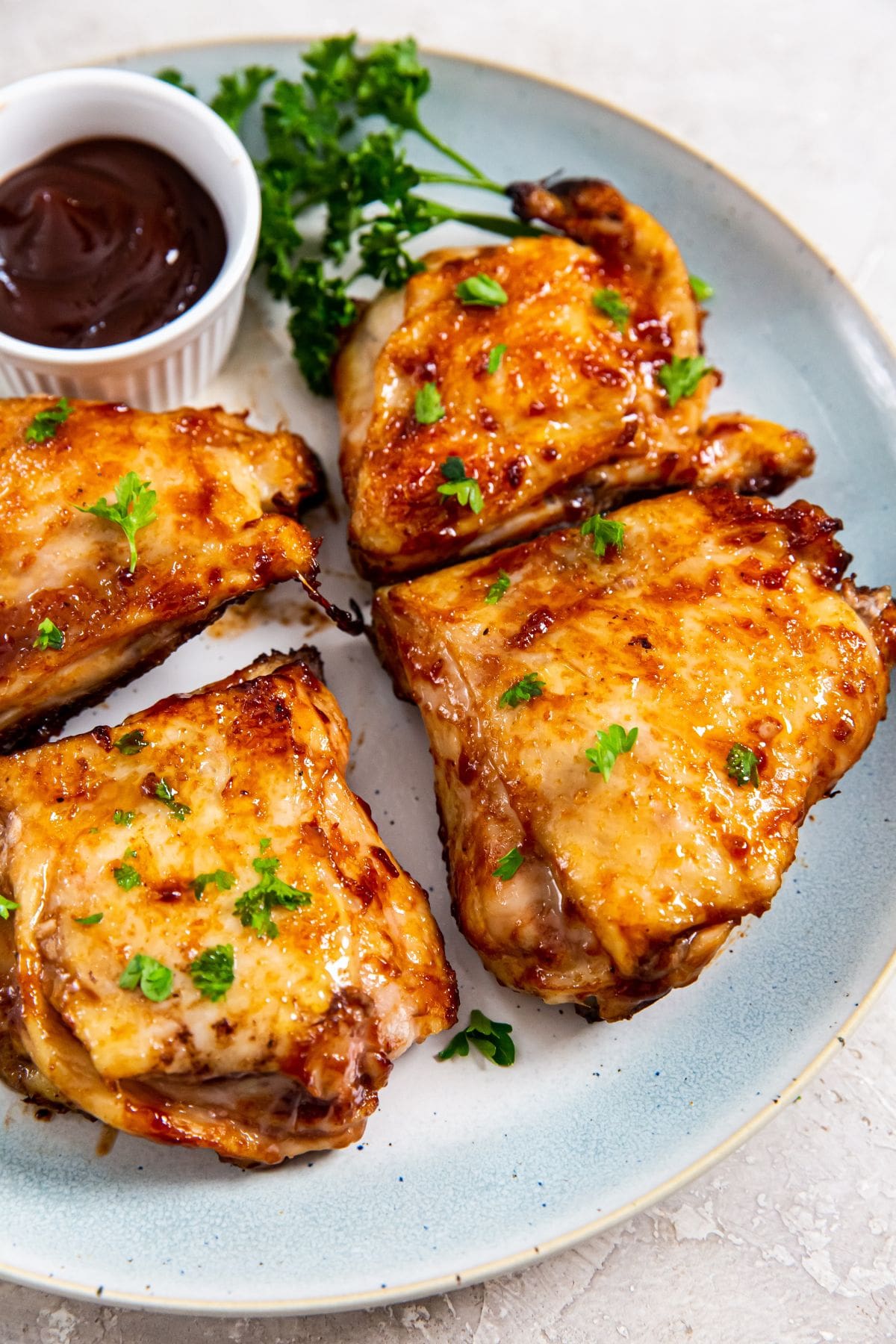 Air Fryer BBQ Chicken Thighs blue plate with chicken thighs and bbq sauce on the plate.