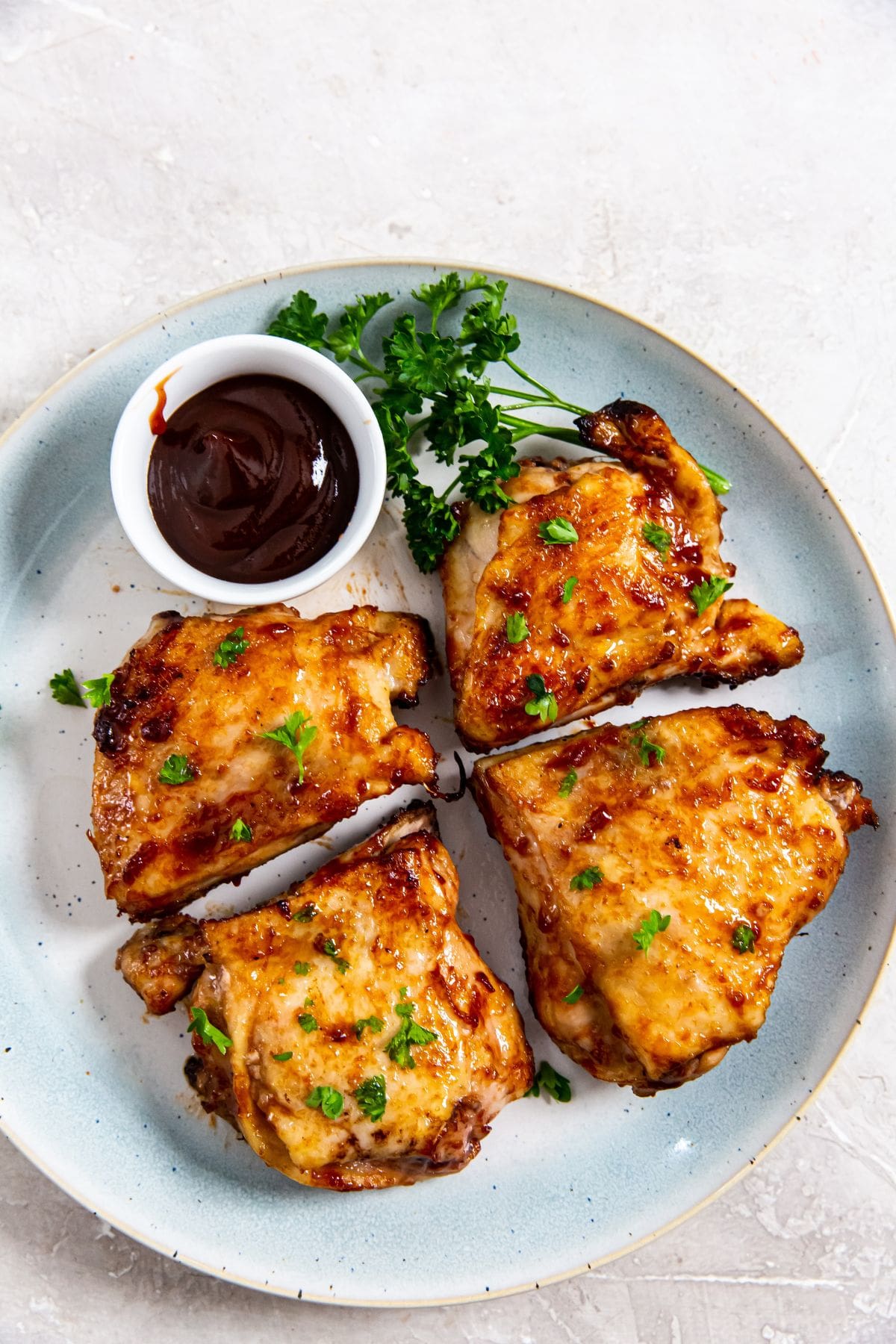 Air Fryer BBQ Chicken Thighs blue plate with chicken thighs and bbq sauce on the plate.