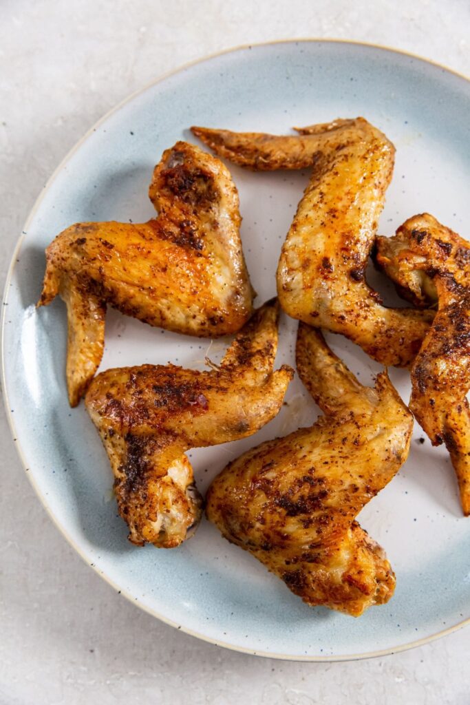Air Fryer Whole Chicken Wings blue plate with chicken and parsley on it.
