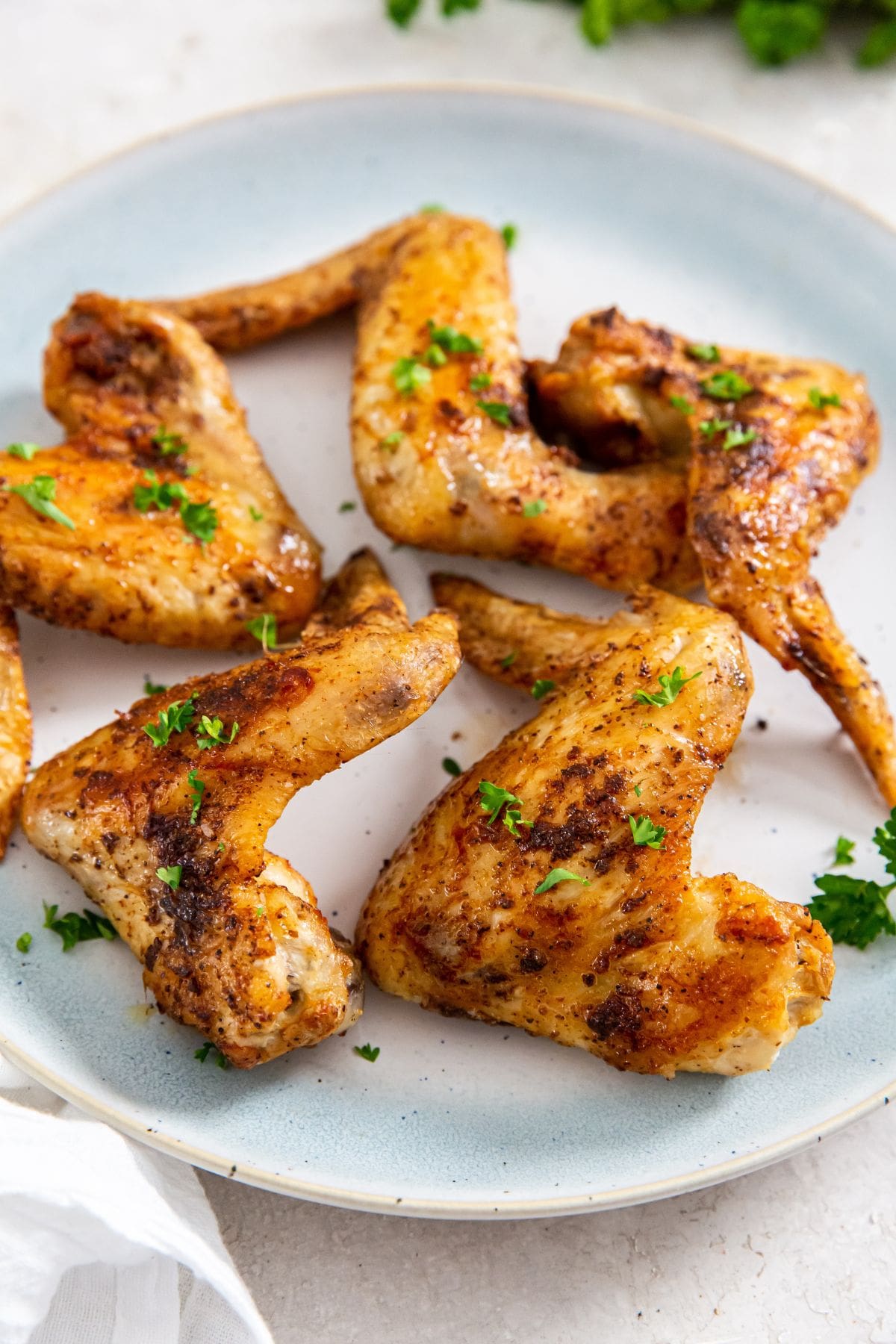 Air Fryer Whole Chicken Wings blue plate with chicken and parsley on it.