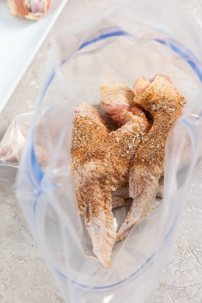 Air Fryer Whole Chicken Wings ziplock back with dry seasoning on top of the chicken
