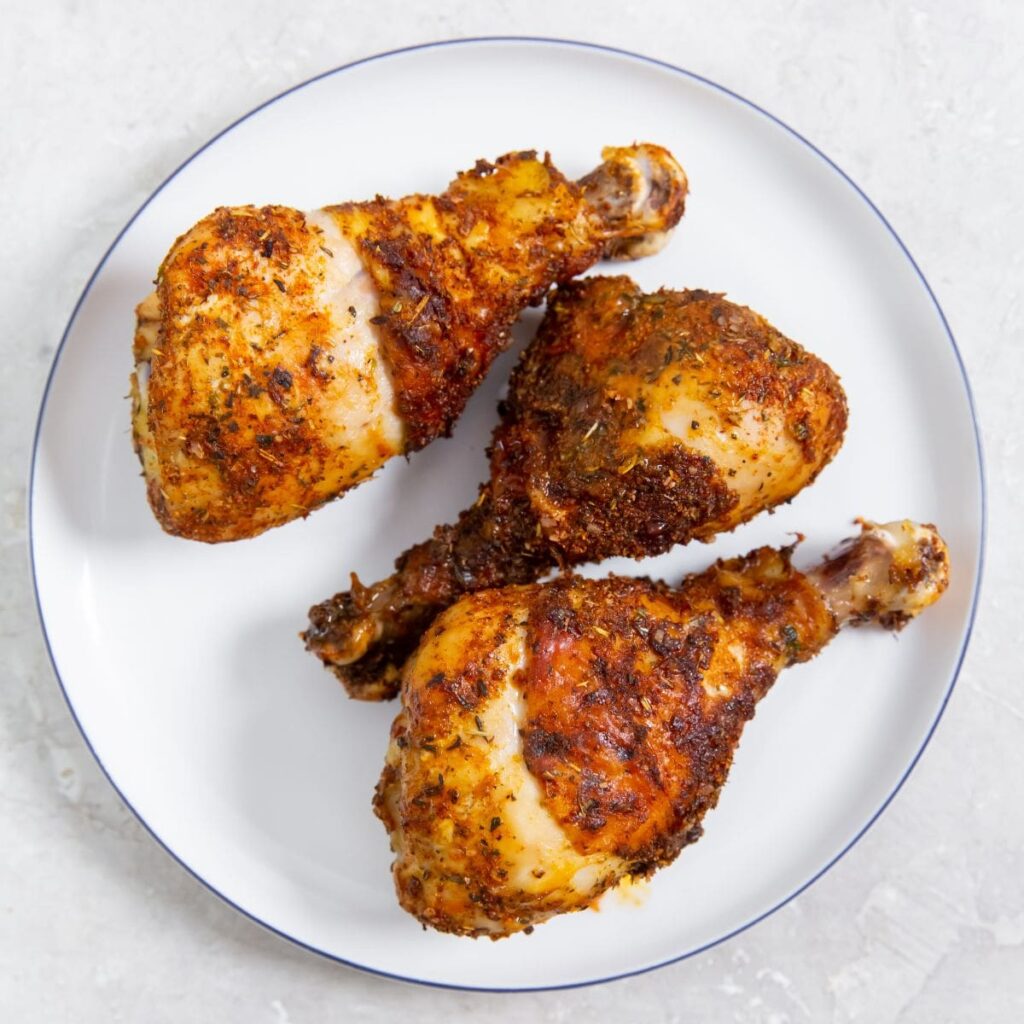 Easy Air Fryer Chicken Legs with Dry Rub white plate with parsley and gray towel in the back