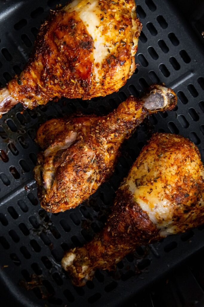 Easy Air Fryer Chicken Legs with Dry Rub black air fryer with cooked chicken inside