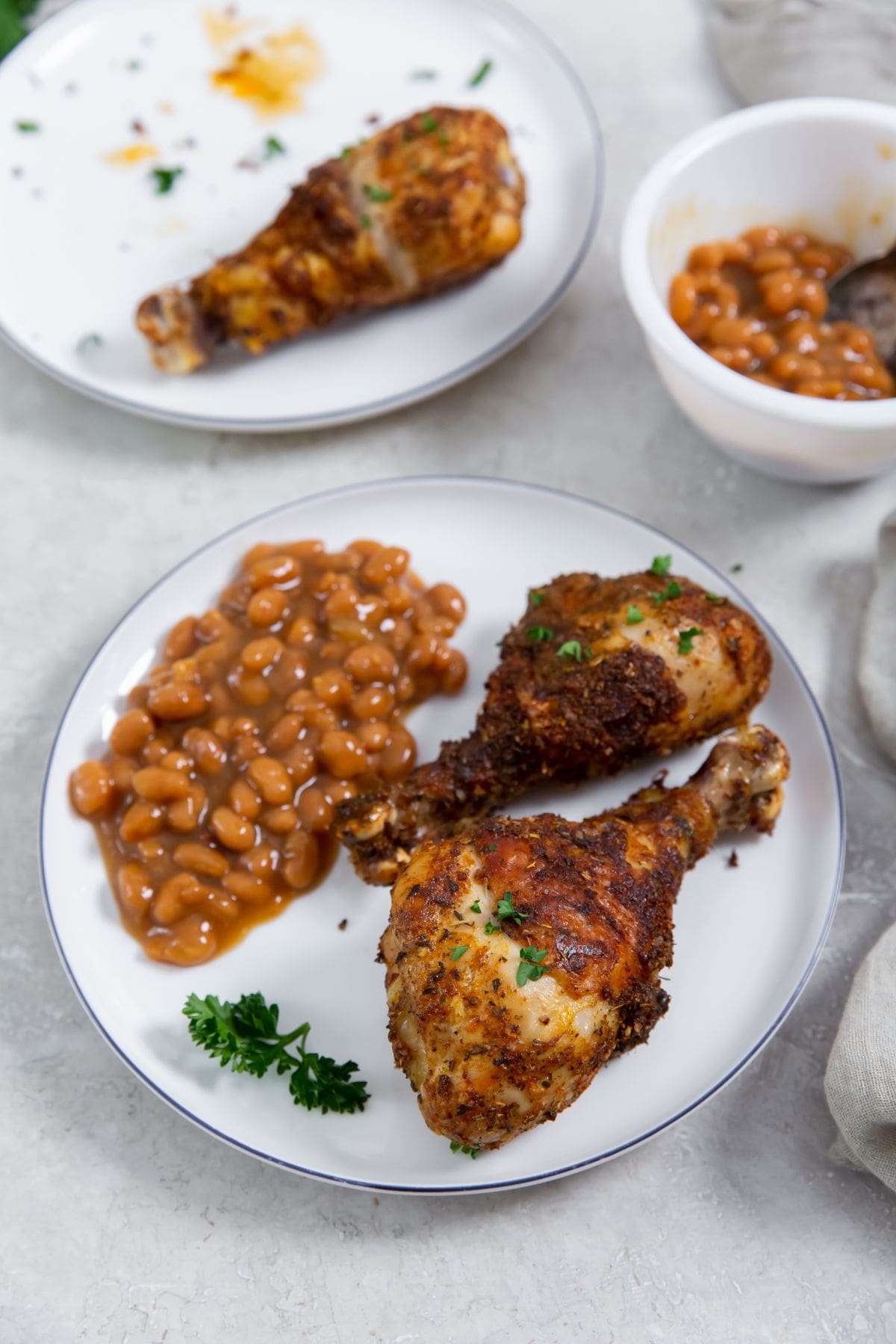 Easy Air Fryer Chicken Legs with Dry Rub white plates with chicken and bake beans on it