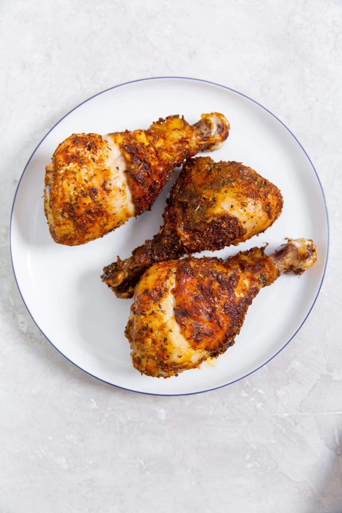 Easy Air Fryer Chicken Legs with Dry Rub white plate with chicken on it.