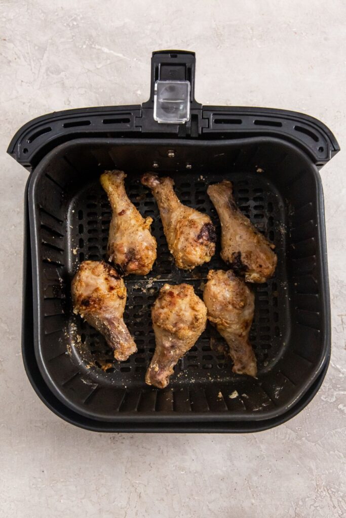 Air Fryer Crispy Chicken Legs black air fryer basket with cooked chicken inside