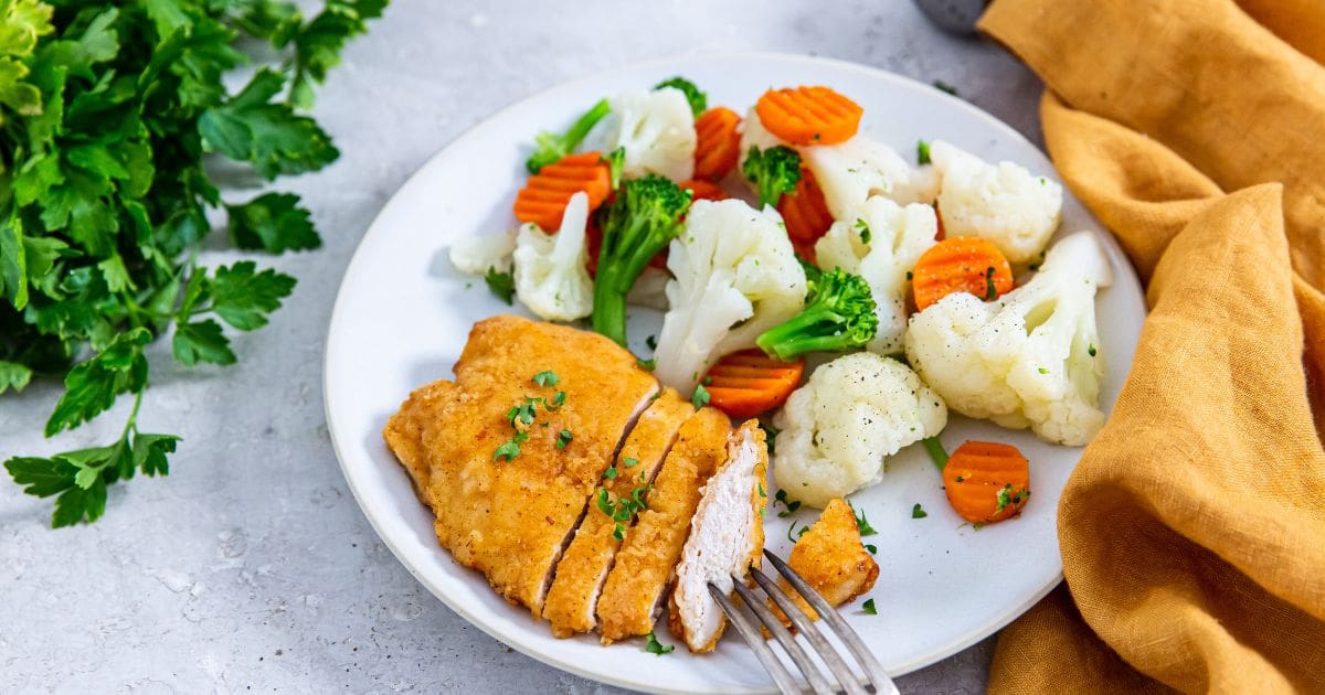 Aldi&rsquo;s Red Bag Chicken in Air Fryer Aldi's Red Bag Chicken breast with carrots and cauliflower on a plate.
